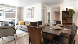 Een moderne eetruimte met een marmeren tafel, zwarte stoelen en een bank op de achtergrond.