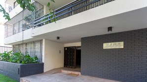 Een modern gebouw met een balkon, een nummerbord en een geplaveid entreegebied.