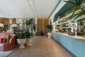 Un hall d’entrée spacieux, doté d’un espace salon, de plantes en pot et d’une vitrine contenant des objets décoratifs.
