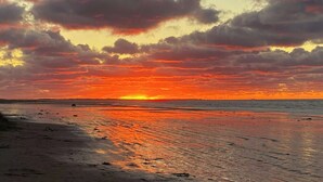 A sunset over a beach with clouds in the sky.