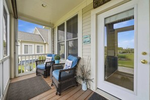 Eine Veranda mit Korbstühlen, einem Willkommensschild und Blick auf ein Haus.