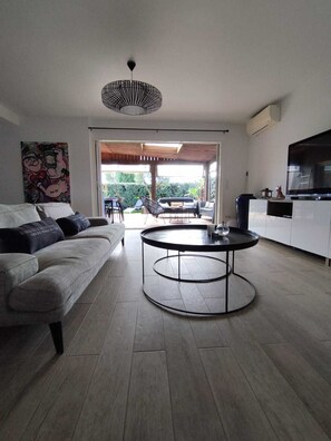 Ein modernes Wohnzimmer mit einer Couch, einem runden Couchtisch und einem Fernseher.