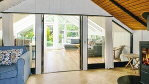 A spacious room with a high ceiling, a built-in fireplace, and a sliding glass door leading to an outdoor area. - 4 Star Holiday Home in Gorlev (Gørlev)