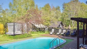 A swimming pool with a wooden deck, lounge chairs, and a covered seating area. - 4 Star Holiday Home in Gorlev (Gørlev)