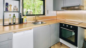 A kitchen with a dishwasher, oven, and a window with a view of trees. - 4 Star Holiday Home in Gorlev (Gørlev)