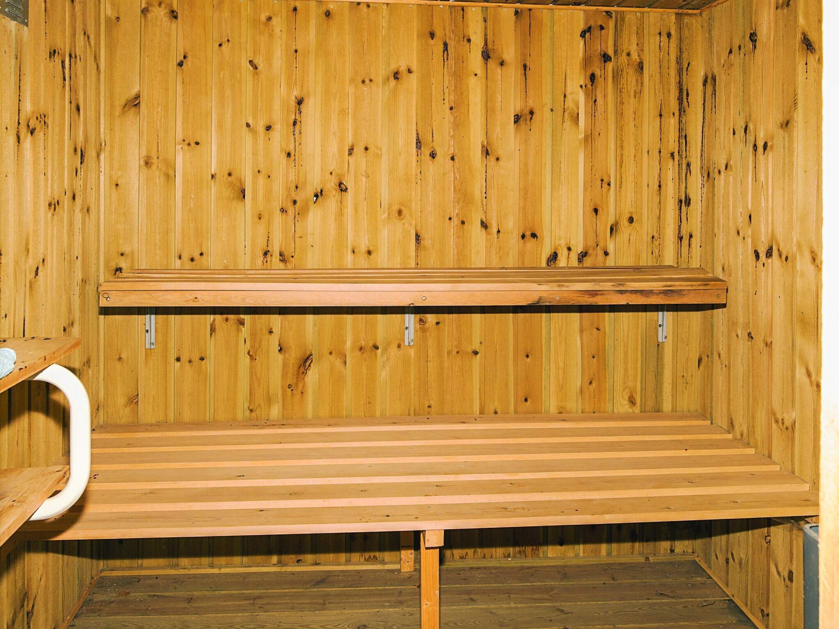 A wooden sauna with a bench and a small shelf.