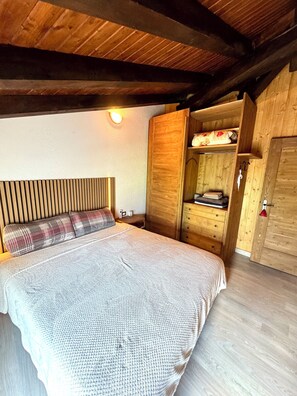 A bedroom with a bed, wooden wardrobe, and a nightstand. - Belle vue des Alpes (Marsan)