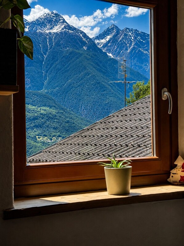 Una ventana con vistas a montañas nevadas y un techo de madera.