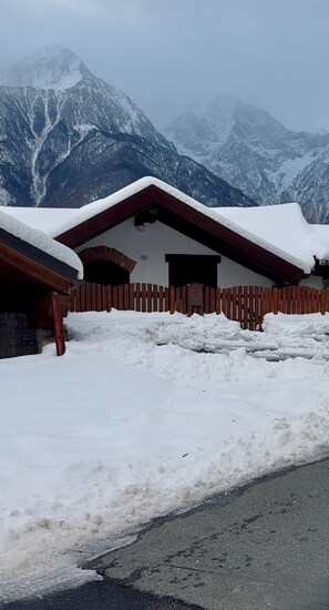 A snow-covered mountain lodge with a wooden fence and a paved road in front. - Belle vue des Alpes (Marsan)