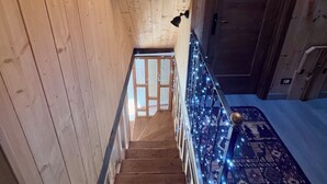 A wooden staircase with a clock on the wall, a railing with lights, and a patterned carpet.
