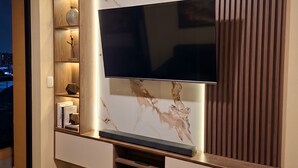 A modern entertainment unit with a flat-screen TV, wooden shelves, and a marble-like wall design. - 3 bedroom apartment (Lima)