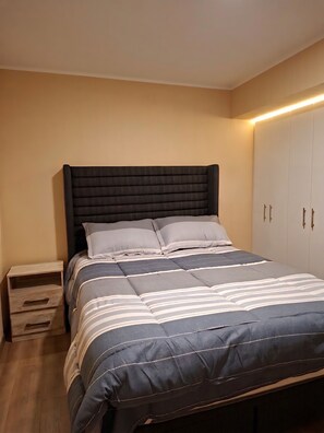 Ein Schlafzimmer mit Bett, Nachttischen und einem Kleiderschrank.
