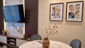 A dining area with a round table, chairs, a vase with branches, and framed abstract art on the wall. - 3 bedroom apartment (Lima)