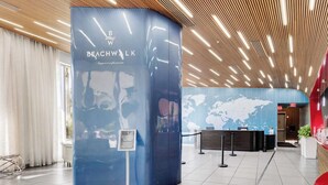 Een moderne lobby met een receptiebalie, een blauwe informatiezuil en een wereldkaart aan de muur.