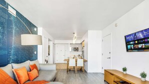 A modern living room with a sofa, a dining area, a kitchen, and a large wall map. - High-Floor 1BR - Intracoastal View - Resort & Pool (Hallandale Beach)
