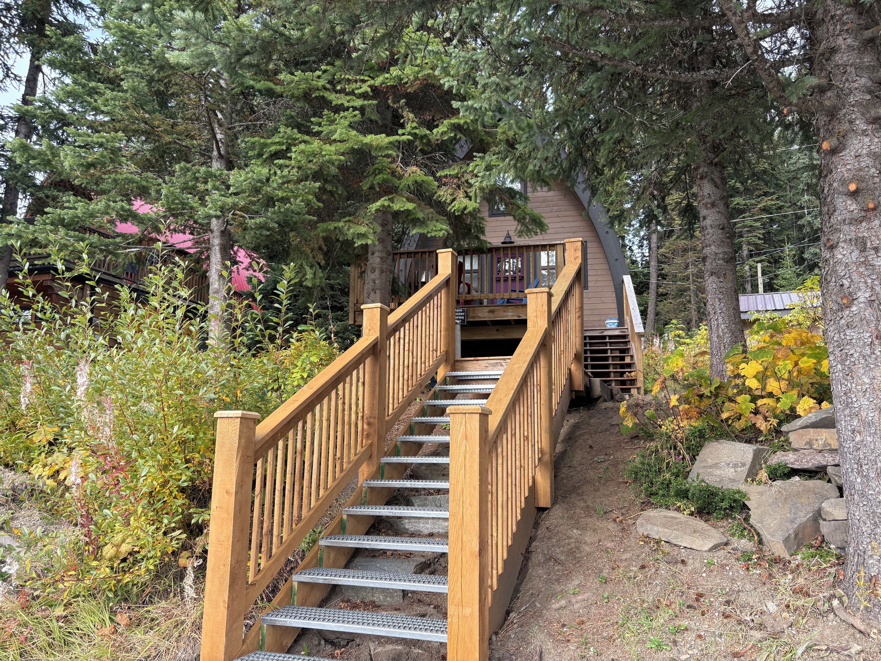 A wooden staircase leading to a building surrounded by trees and vegetation.