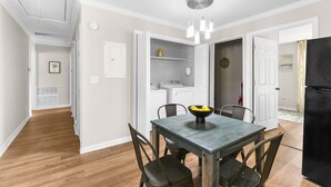 Eine moderne Küche mit weißen Schränken, einem schwarzen Kühlschrank und einem Essbereich mit Tisch und Stühlen.