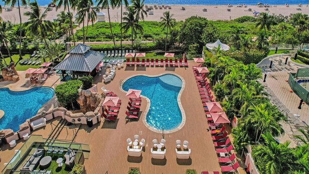 Um resort com várias piscinas, áreas de descanso e vista para a praia.