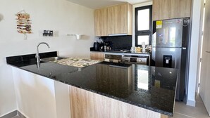Eine moderne Küche mit einer zentralen Kochinsel, Edelstahlgeräten und hellen Holzschränken.