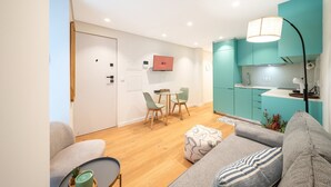 Uma sala de estar moderna com sofá, mesa de centro e área de refeições com cadeiras e uma pequena mesa.