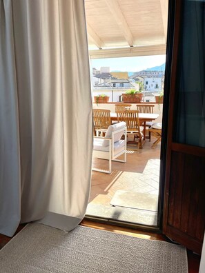A room with a sliding glass door leading to an outdoor patio with a table and chairs. - Seaview Downtown (Palermo)