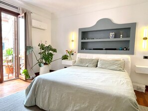 Una camera da letto con un letto, comodini, una mensola a parete e piante in vaso.