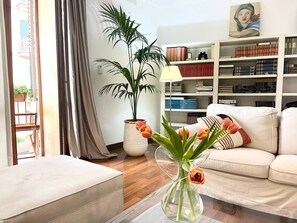 A living room with a sofa, a coffee table, a bookshelf, a potted plant, and a vase with flowers. - Seaview Downtown (Palermo)