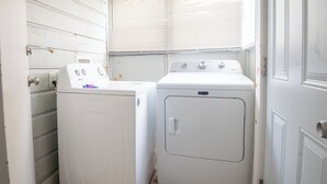 Ein Waschraum mit zwei weißen Geräten, eine Waschmaschine mit Bedienfeld und eine weitere mit Tür.