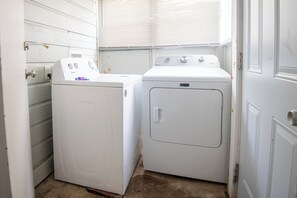 Un cuarto de lavandería con dos electrodomésticos blancos, uno con un panel de control y el otro con una puerta.