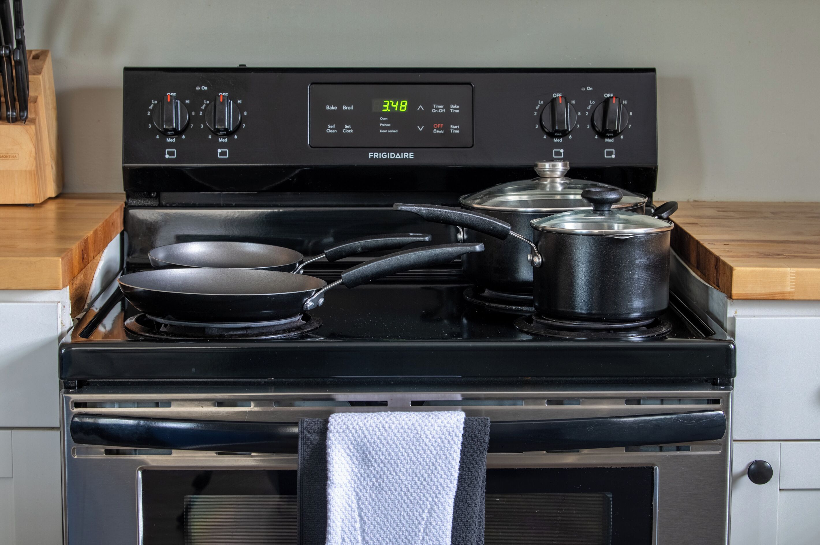 Una cocina con estufa negra, dos ollas y una sartén.