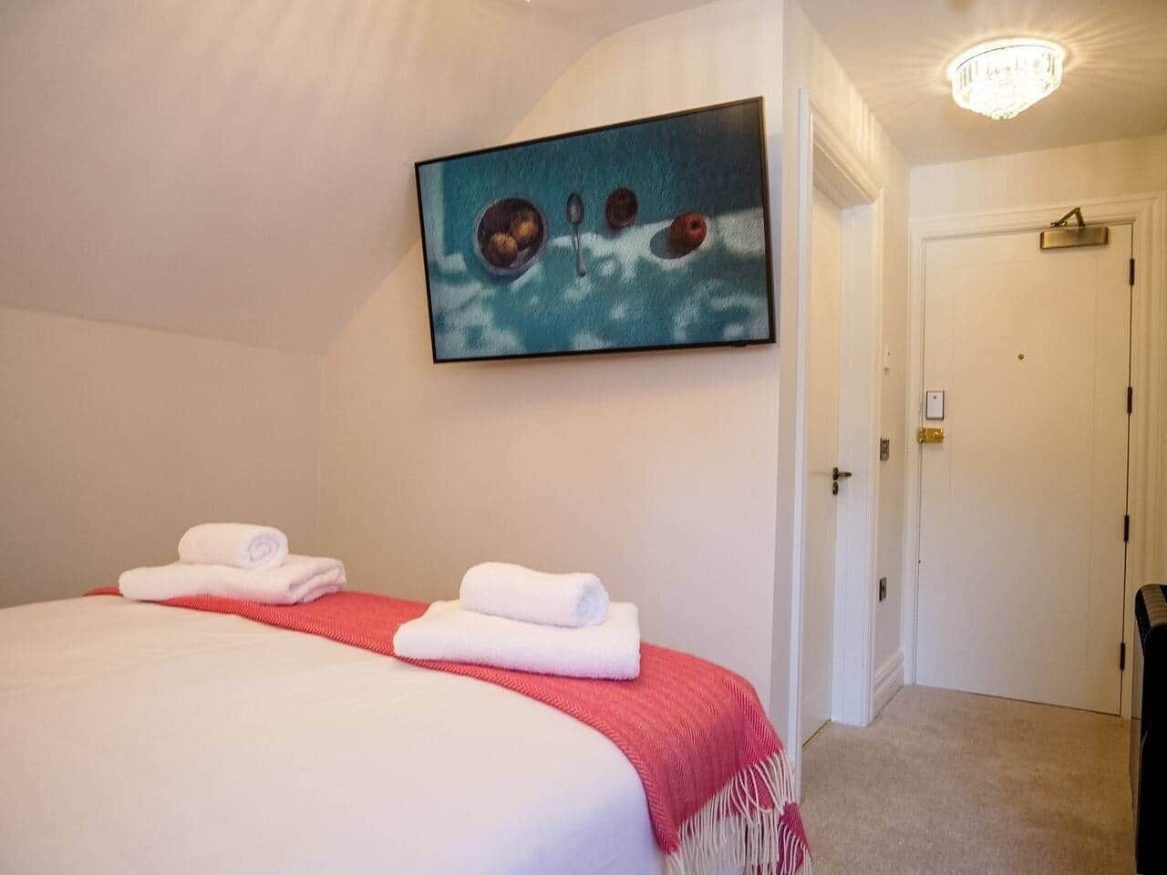 Ein Hotelzimmer mit zwei Betten, einem Bild über den Betten und einer Tür rechts.