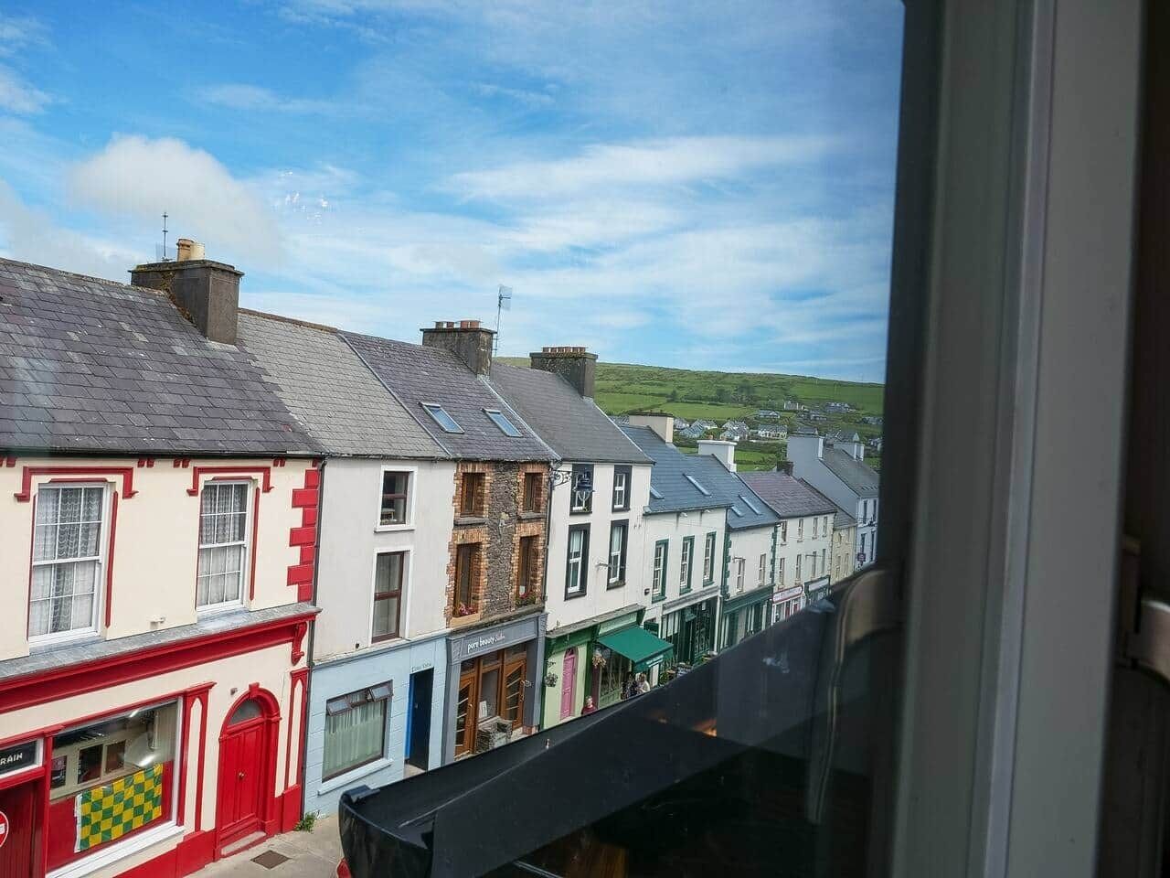 A row of buildings with a shop on the left, a restaurant in the middle, and a view of a green landscape in the distance.