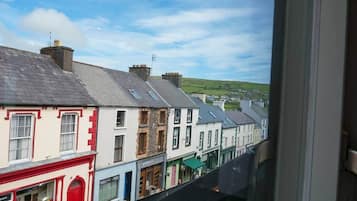 A row of buildings with a shop on the left, a restaurant in the middle, and a view of a green landscape in the distance.