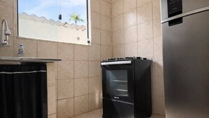 Une cuisine avec une fenêtre, un réfrigérateur et une cuisinière.