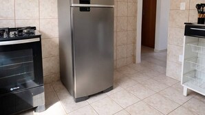 Une cuisine équipée d’un réfrigérateur en acier inoxydable, d’un four noir et d’une armoire blanche avec des étagères.