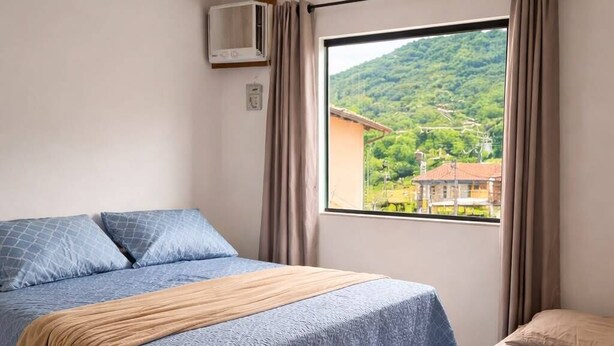 Une chambre avec deux lits, une fenêtre donnant sur un paysage verdoyant et un climatiseur fixé au mur.