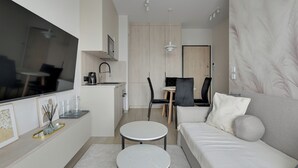 Una sala de estar moderna con un sofá, una mesa de centro, un televisor y un comedor con sillas y una mesa.