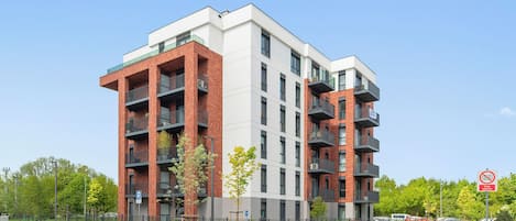 A multi-story building with balconies, a parking area, and a no parking sign.