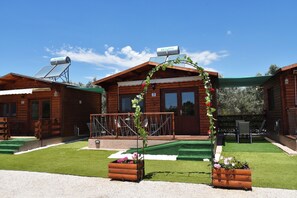 A wooden cabin with a balcony, solar panels, and a number 3 sign.