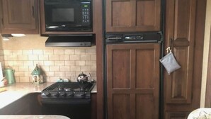 Une cuisine compacte équipée d’un four à micro-ondes, d’une cuisinière et d’un lave-vaisselle.