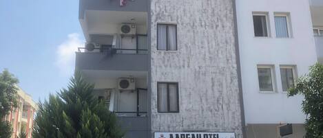 A multi-story building with balconies, air conditioning units, and a sign for 'AARGAU OTEL.'