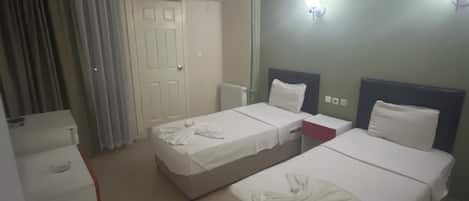A hotel room with two beds, a wardrobe, a mirror, and a ceiling fan.