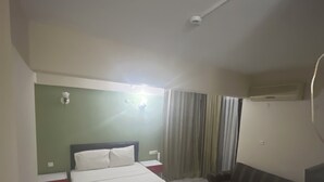 Une chambre d’hôtel équipée d’un lit, d’un bureau, d’une chaise, d’un petit réfrigérateur et d’une fenêtre avec des rideaux.