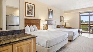 Une chambre d’hôtel avec deux lits, un coin cuisine et un balcon avec vue.