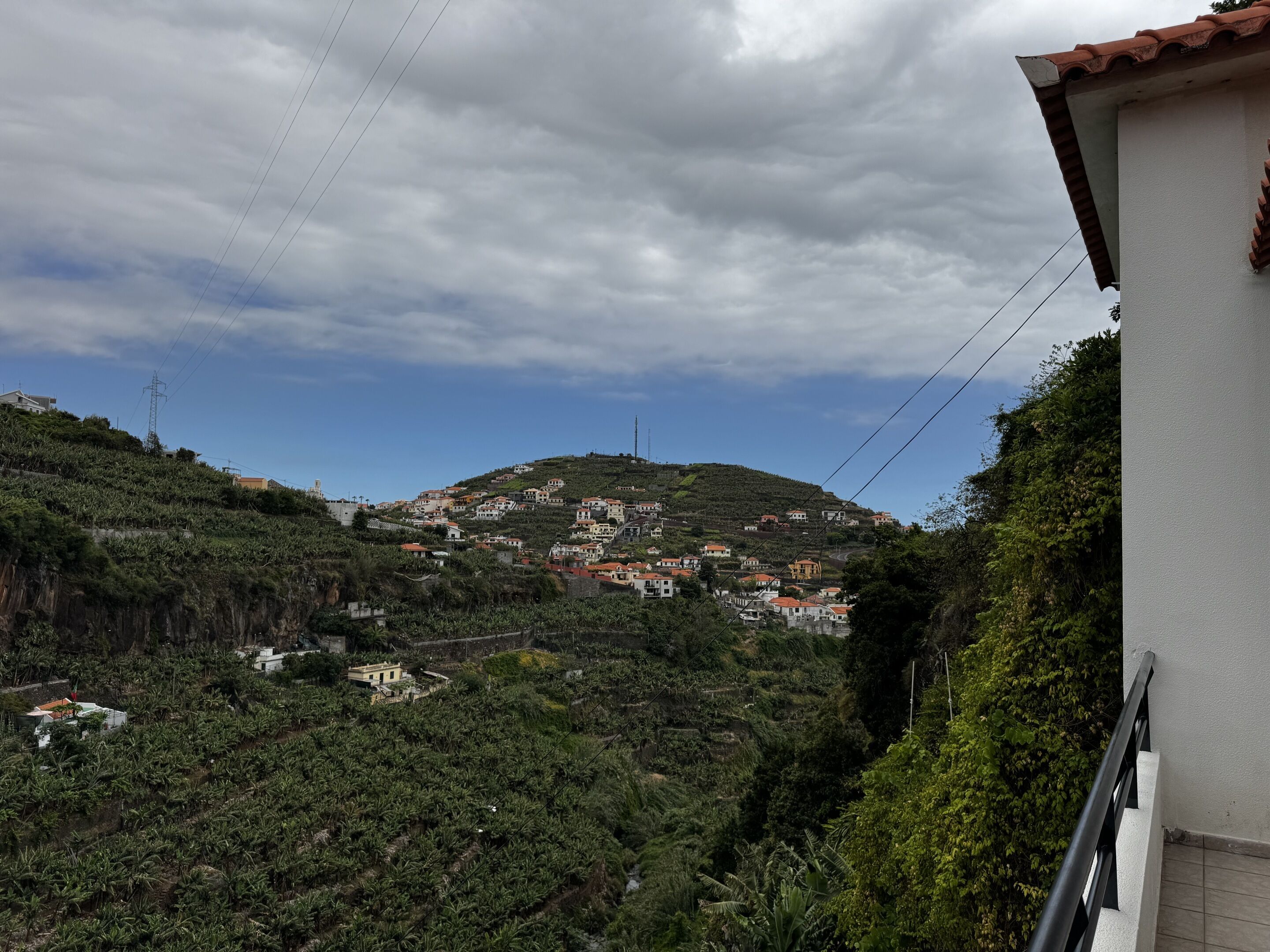 Un village perché sur une colline, avec des maisons, une ligne électrique et un bâtiment doté d’un toit rouge.