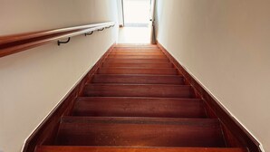 Eine Holztreppe mit Handlauf, die zu einem hellen Außenbereich führt.