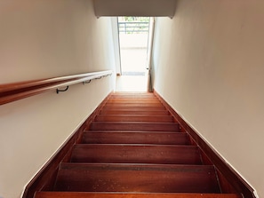 A wooden staircase with a handrail, leading to a bright area outside. - Wolf Villa (Câmara de Lobos)