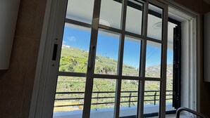 Ein Fenster mit Blick auf eine Hügellandschaft und Gebäude.