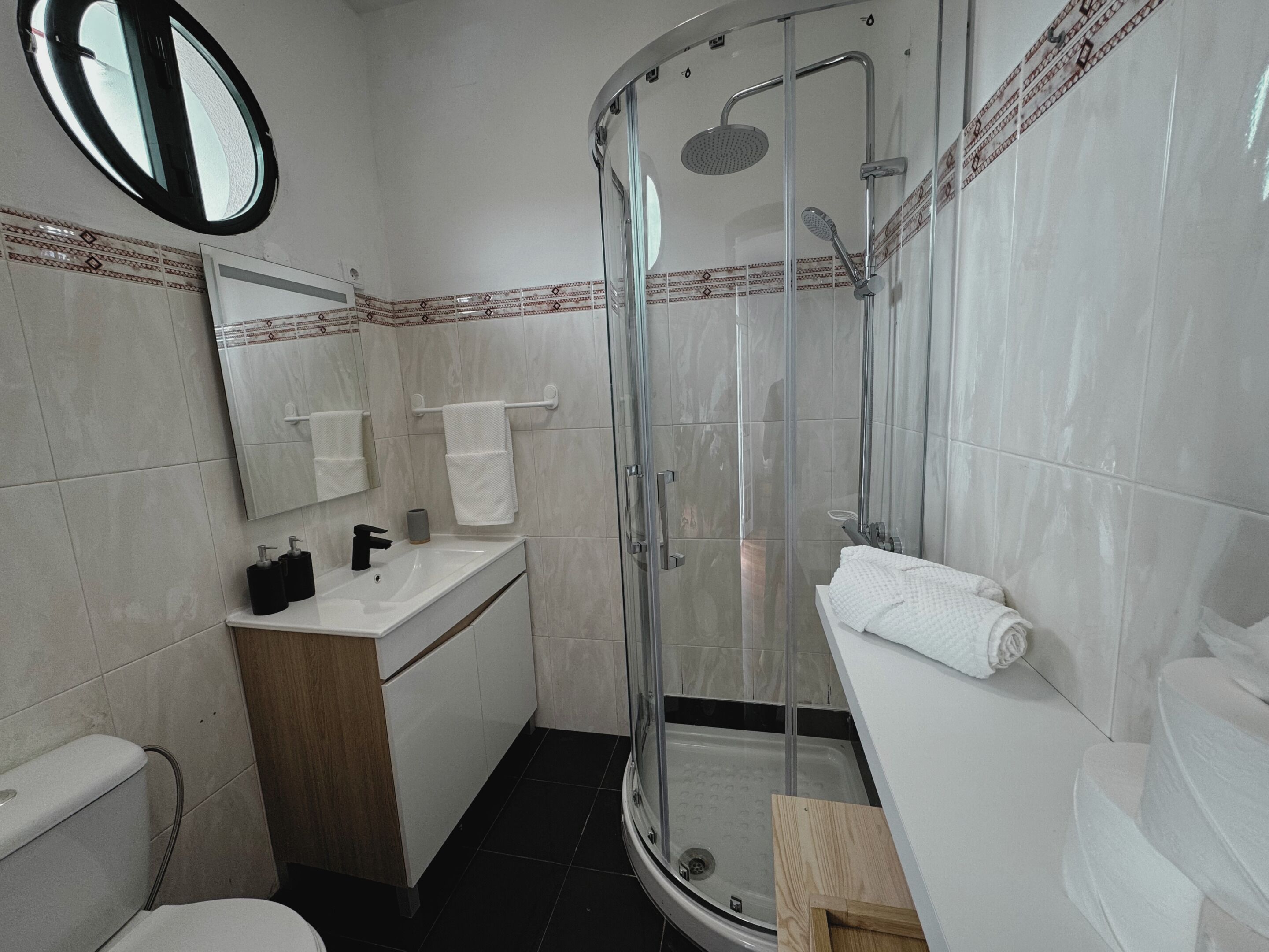 Une salle de bain moderne avec une douche à parois de verre, un lavabo avec un miroir et des toilettes.