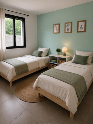 Ein Zimmer mit zwei Betten, einem Fenster, einer Wand mit gerahmten Tierabbildungen, einem Nachttisch mit Lampe und einem gewebten Teppich.